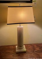 Full lamp showing the lighted rectangular shade and marble column base on wooden table