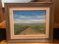 Front view of the framed oil painting showing landscape and ornate frame