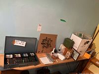 Shelf with assorted hardware such as screws, binder clips, a small glue bottle, boxes, and other miscellaneous items, alongside the pastel case.