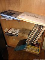 Shelf with Glenn Miller album on top with various magazines and records below, box labeled 'Vintage LPs' and binders