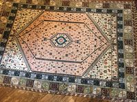 Top-down view of full rug showing pink central hexagonal medallion and border bands