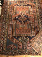 Full view of rug laid flat on wood floor showing central medallion and border motifs