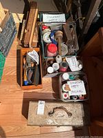 Overall lot of sculpture supplies including labeled containers and boxes with solvents, polishing items, casting materials, brushes, wax, and patina supplies next to metal toolbox and wood chisels