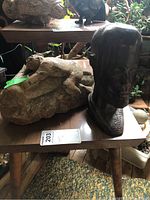 Two sculptures on a wooden table, including a stone shaman/fish figure and tropical hardwood head bust.