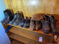Full view of all shoes arranged on wooden shelf showing various styles and colors, mostly in brown and black.