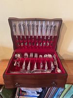 Open wooden chest showing twelve knives in upper rack and assorted flatware in bottom tray