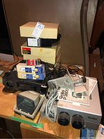 Overall view of the Kodak and Rollei slide projectors with trays, cables, and lamp boxes on a wooden table.