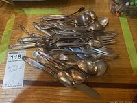 Pile of assorted sterling flatware on wooden surface