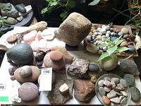 Overview of multiple stones on a table including smooth round stones, rough stones, and pink quartz clusters.