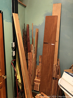 Tall stack of assorted wood boards and strips leaning against wall