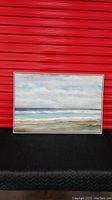 Full view of the abstract beach scene painting in white frame against red background.