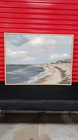 Full view of seaside landscape artwork on canvas with driftwood style frame placed against a red background.