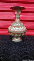 Side view of the hand-painted brass vase showing the detailed painted motifs and bulbous shape