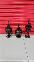 Full view of the three black lidded decorative vases with glossy finish, showing different heights
