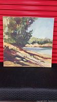 Front view of square landscape canvas art depicting river bank with trees, water, and sky in earth tone colors.