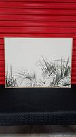 Frontal view of tropical foliage canvas print showing detail of palm leaves and wood-look frame.