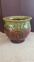 Side angled view showing the detailed embossed foliage pattern and the brown to green blended glaze on the jardiniere exterior.