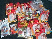Top down view of multiple 3M Command hooks packages, showing various unopened sets including large, medium, and small hooks for picture hanging. Packaging is new and sealed.