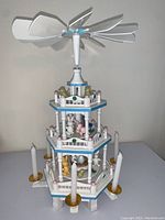 Full front view showing the 3 tiers with painted wooden Easter figurines and candle holders, with large propeller on top.