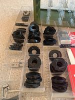 Detailed view of multiple black plastic and metal stitch pattern cams arranged in clear trays, part of the decorative sewing machine accessory set.