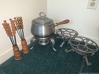 Full set showing fondue pot on stand with two iron warmers and twelve forks in wooden holders