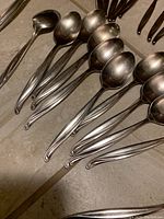 Close up of soup spoons with curved handles showing stainless steel finish.