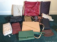 Overview of various purses and wallets spread out on green carpet with white wall background