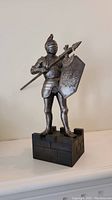Full front view of the knight figure standing on the carved wooden base with battle axe and shield.
