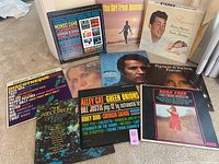 Photo showing 11 vintage vinyl record album covers arranged on floor, visible titles include Mondo Cane, The Girl From Ipanema, Dean Martin & Frank Sinatra, Herb Alpert, Casino Royale, Born Free, The Association Greatest Hits, Discotheque, Alley Cat Green Onions.