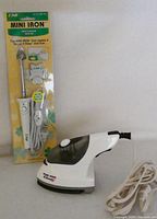 Photo of CNI Mini Iron in original packaging with temperature control and compact size.