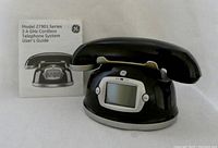 Front view of black GE cordless telephone base with digital display and user's guide.