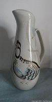 Front side of large ceramic pitcher showing detailed 'Bob White' bird artwork in brown and blue on a speckled creamy white base.