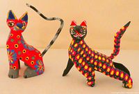 Two Oaxacan hand painted cat figurines, side and front views showing colors and tail details.