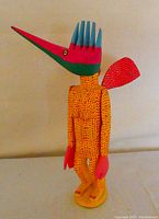 Front side view of the colorful Oaxacan wooden figure with long pointed bird-like head and wings.