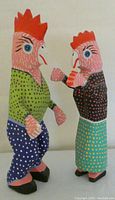 Front view of the colorful hand painted rooster and hen dancing couple figurines. Shows detailed painting and clothing patterns.