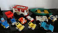 Full view of 12 vintage Fisher Price Little People vehicles arranged on a black surface showing the variety of items included