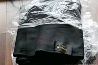 Folded black cashmere fabric wrapped in plastic showing woven label