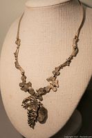 Front view of the handcrafted Jurman necklace on display bust, showing the pendant with intricate organic shapes and detailing.