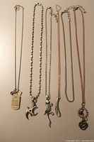 Six necklaces laid out on a flat surface showing pendants and chain styles.