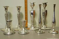 Full view of 7 silver candlesticks and bud vases showing set variety and sizes compared to ruler