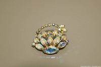 Front view of Sherman brooch showing sparkly multicolored Aurora Borealis rhinestones arranged in a symmetrical design with gold-tone metal setting.