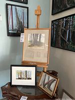 Three framed mixed media art pieces by Donald Gotz on furniture with easel in background, showing titles and general appearance, with visible frames and artworks.