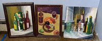 Three oil paintings arranged side by side showing liquor bottles, fruit, and window still life.