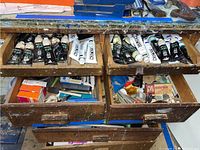 Open wooden drawers displaying black and white acrylic paint tubes