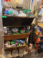 Three stacked storage bins filled with assorted hardware items, plastic jars and tools