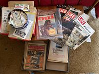Wide view of the lot shows magazines including Oui, LIFE, The Boston Globe, and S&H Stamps books, newspapers spread on carpet