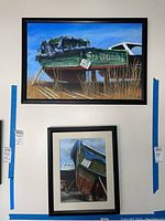 Two framed paintings by Donald Gotz hanging on a wall showing boats, one horizontal titled Sea Witch, one vertical titled For Sale.