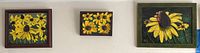 Three framed sunflower paintings hung on wall, showing abstract yellow sunflowers with dark centers in different compositions and frames.