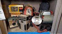 Photo showing Mercury Satellite 127, Kodak Bantam in original box, Brownie Tarflash camera with visible mold, Stellar camera box, Anscoflex II camera and black camera case.