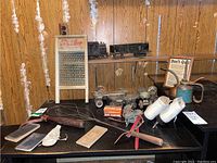 Wide view of the lot items including washboard, roller skates, ice skates, train cars, oil cans, pocket books, baby shoe, skate sharpener, and rug beaters.